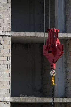 A crane hook and a building under construction Stock Photos