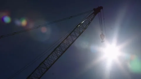 Crane hook on building construction site with bright sun and lens flare in sky Stock Footage 130377025