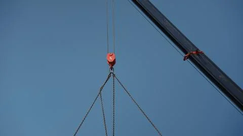 Crane hook lifting heavy chains against blue sky Stock Photos