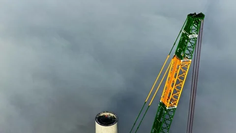 Crane installing a section of a large wind turbine tower under construction Stock Footage 333318432