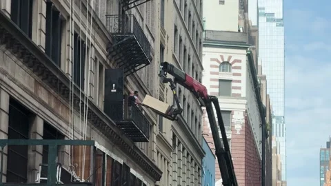Crane Lifting Box to Workers on Fire Escape in Manhattan Urban Construction Stock Footage 346494345