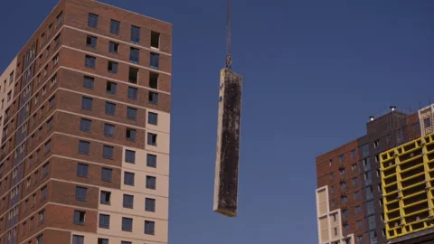 Crane lifting concrete column between residential buildings Vidéo 347160214