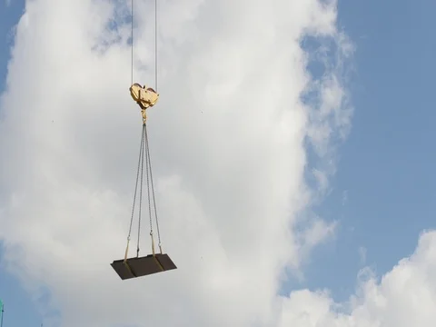 A crane lifting heavy equipments on a construction site - in front of blue sky Stock Footage 77806412