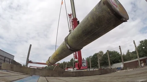 Crane lifting large pipe off flatbed trailer Stock Footage 84264847