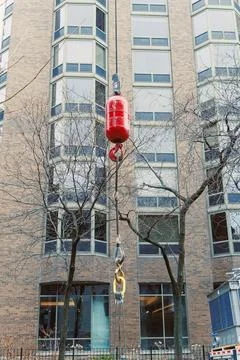 A crane is lifting a load in front of a large brick building. Workers are pre Stockfoto's