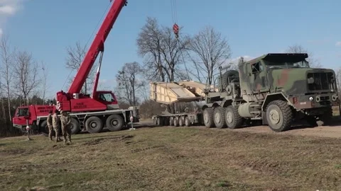 Crane lifting M1074 joint assault bridge from Oshkosh M1070 low-loader trailer Stock Footage 267835678