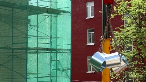 Crane lifting metal construction materials near red brick building Stock Footage 341833825