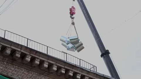 Crane lifting metal ventilation ducts to the rooftop of an old brick Stock Footage 341833976