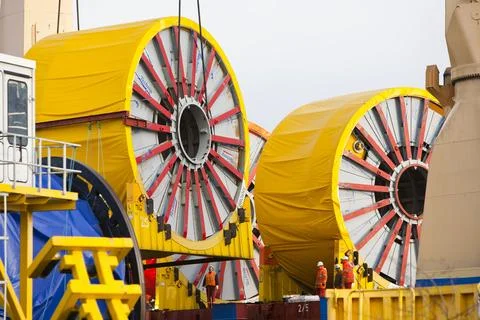A crane lifting offshore cabling onto a ship at Duco Ltd, an offshore supply  Stock Photos