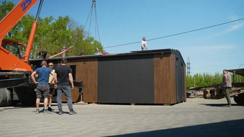 Crane lifting prefabricated modular house, construction workers supervising Stock Footage 316717554