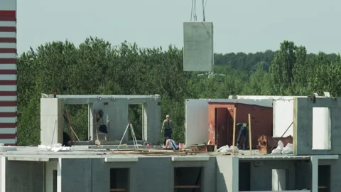 Crane Lifts Concrete Panel Over Construction Site. Workers On Partially Built Stock Footage 322094955