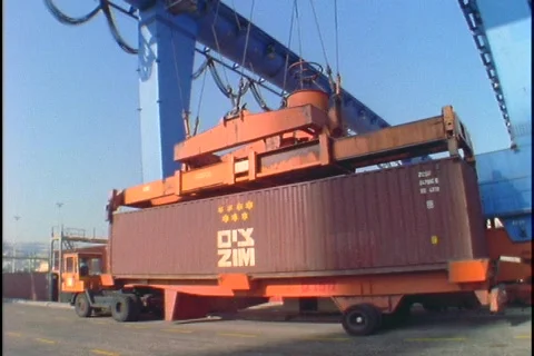 A crane lifts a large cargo container from the back of a flatbed truck. Stock Footage 337616