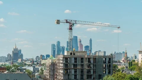 A crane lifts the load on the construction site on sunny day with Moscow skyline Stock Footage 112023284