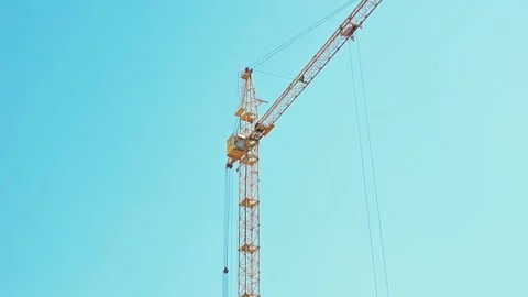 A crane lifts materials above the construction site as workers coordinate from Video stock 339090589