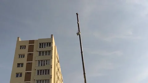 A crane lifts various materials on a block of flats in Romania Stock Footage 218236999