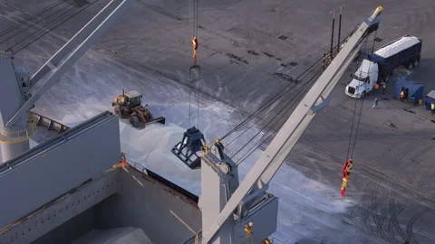 Crane loading bulk cargo of hydrated lime into a ship's hold at an industrial Stock Footage 345905345