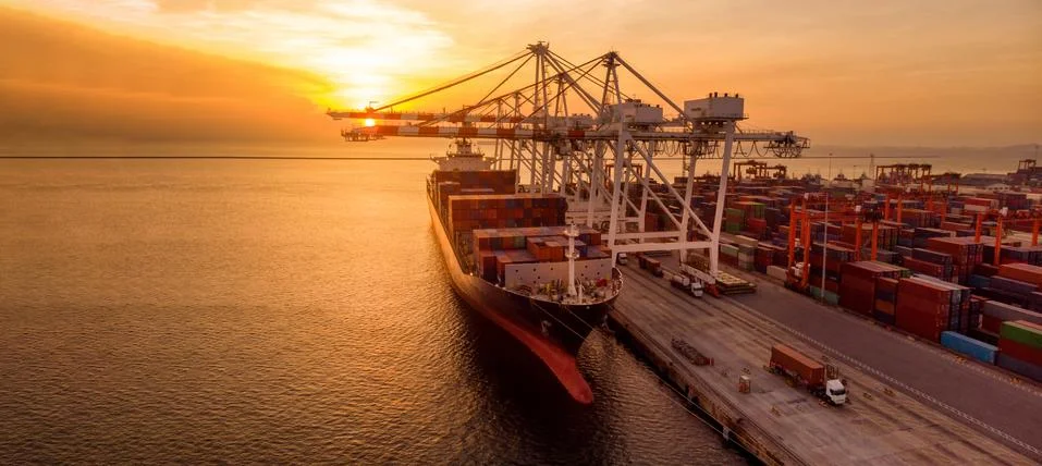 Crane loading cargo container to container ship in the international terminal Foto stock