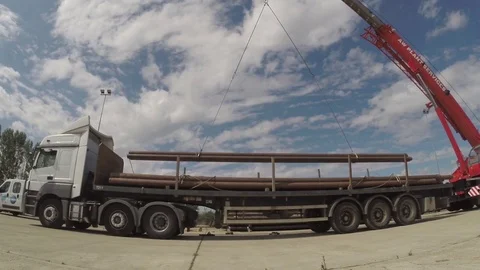 Crane loading offshore pipes onto flatbed truck Stock Footage 84302452