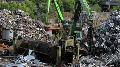 Crane loading scrap metal into metal compactor at scrapyard Stock Footage 25596316