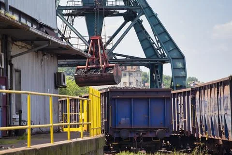 Crane loading train wagon with coal from barge Stock Photos