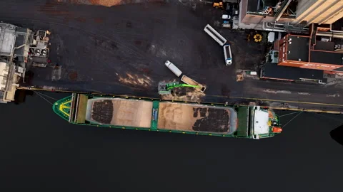 Crane loading wood chips onto barge at port Stock Footage 297054851