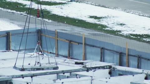 Crane lowering concrete slab onto building foundation at winter construction Video stock 342922786