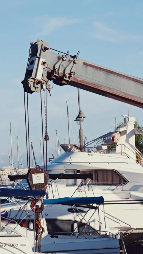 A crane machine moving down near boats docked in a harbour. Vertical Stock Footage 301734775