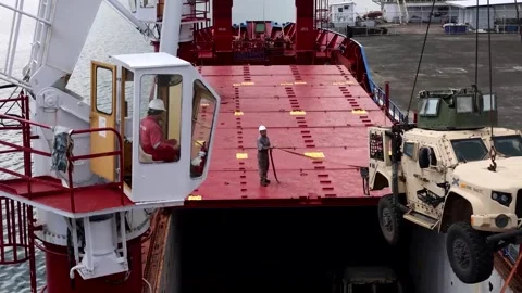 Crane maneuvering Joint Light Tactical Vehicle for loading onto commercial ship Stock Footage 278220843