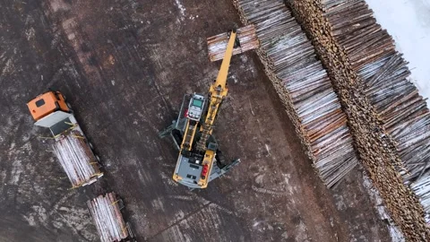 A crane-manipulator unloads timber from a timber truck into stacks. Copter Video stock 294048339