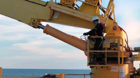 Crane operator operate crane lifting cargo from boat to platform with blue sky l Stock Footage 118486794