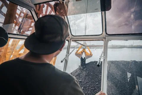 Crane operator unload coal skillfully navigates controls a crane, lifting large Stock Photos