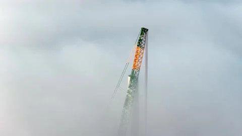 Crane pokes through thick cloud cover during wind farm development Stock-Footage 330868206