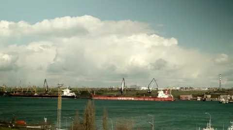 Crane in port loads big ship and tow boat tows big ship Stock Footage 64128719