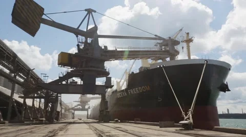 Crane in port loads grain on big ship Stock Footage