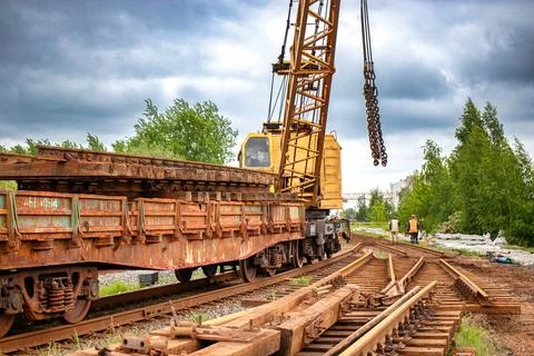 A crane is positioned on a train track, conducting maintenance work, with rai 스톡 사진