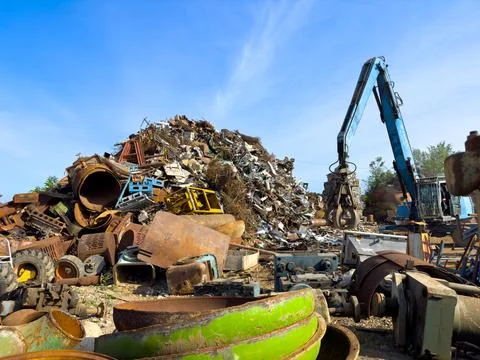 A crane is processing a mountain of scrap metal in the sky Stock Photos