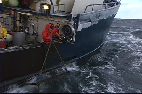 A crane pulls a crab-pot full of fish aboard a vessel. Stock-Footage 552605