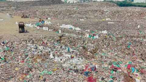 Crane Pushing And Segregating Garbage Across An Active Waste Dump Yard Stock Footage 341462534