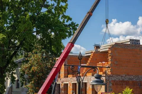 A crane raises construction materials for a new residential building while .. Stock Photos