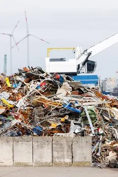 Crane at recycling facility loading large scrap metal pile Stock Photos