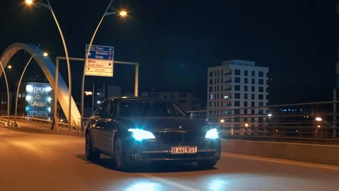 Crane rolling shot of a BMW 7 Series luxury car driving on a bridge at night Video stock 125524052
