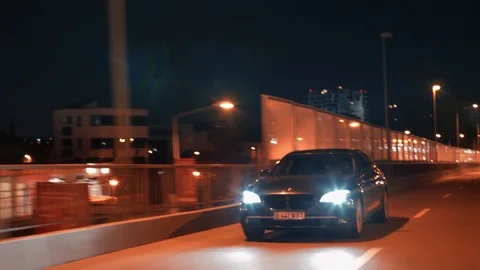 Crane rolling shot of a BMW 7 Series luxury car driving on a bridge at night Video stock 125524088