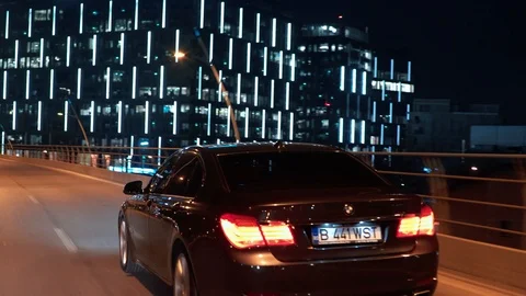Crane rolling shot of a BMW 7 Series luxury car driving on a bridge at night Stock Footage 125524285