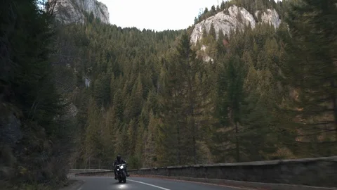 Crane rolling shot of a motorcycle driving on a mountain road during autumn Stock Footage 122644863