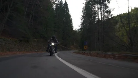 Crane rolling shot of a motorcycle driving on a mountain road during autumn Stock Footage 122644945