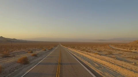 Crane shot of car taking off onto deserted road in desert Stock Footage 83929350