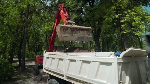 Crane shot, excavator digs ground and loading tipper truck at construction site. Stock Footage 76762704