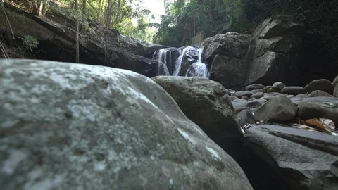 Crane shot of waterfall in rainforest with rocks in foreground Stock Footage 87192544