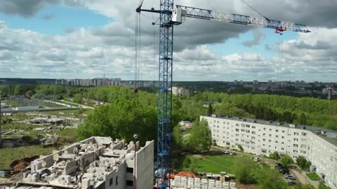 A crane is on top of a building under construction in a city area with trees and Stock Footage 230364073