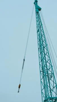Crane tower with hook and cable against clear blue sky background Stock Photos